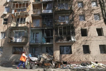 Une habitante passe devant un immeuble touché par des frappes ukrainiennes à Koursk, le 16 août 2024 en Russie