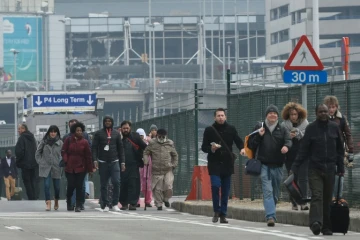 Des passagers évacuent l'aéroport de Bruxelles, le 22 mars 2016 après deux explosions