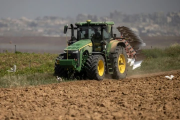 Un agriculteur en tracteur dans un champ agricole près de la frontière entre le sud d'Israël et la bande de Gaza, le 21 mai 2025