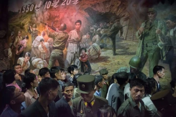 Un groupe de visiteurs passe devant un tableau représentant des soldats américains s'apprêtant à tuer des civils nords-coréens, le 24 juillet 2017 au Musée des atrocités de guerre américaines à Sinchon, en Corée du Nord