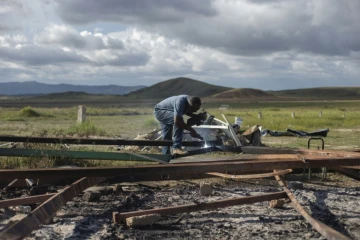 Un homme découpe la structure d'un abri utilisé par des réfugiés vénézuéliens et détruit par des Brésiliens, le 20 août 2018 à Pacaraima, au Brésil