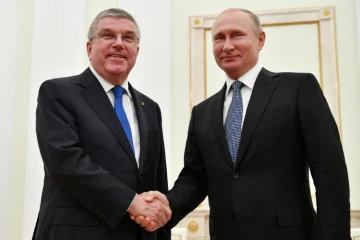 Le président russe Vladimir Poutine (d.) serre la main du président du Comité international olympique (CIO) Thomas Bach lors de leur rencontre au Kremlin à Moscou, le 15 juillet 2018