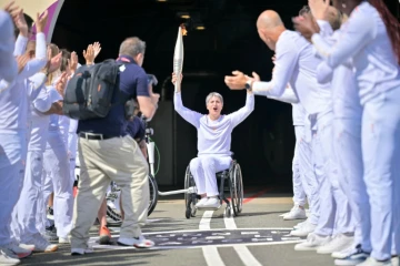 Emmanuelle Assmann, médaillée en escrime-fauteuil, brandit la flamme paralympique 
au terme d'une traversée inédite par le tunnel sous la Manche, le 25 août 2024 à Coquelles dans le Pas-de-Calais