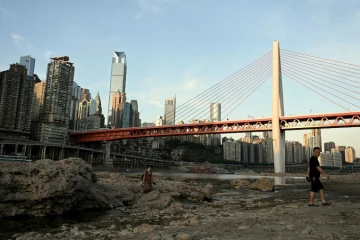 Des passants traversent le lit asséché de la rivière Jialing, un affluent du fleuve Yangtsé, dans la ville de Chongqing en Chine, le 24 août 2022