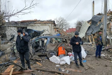 Trois hommes devant des ruines provoquées par un bombardement des forces russes à Jitomir, en Ukraine, le 2 mars 2022