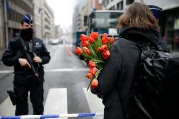 Une femme arrive avec des fleurs à la station de métro de Maelbeek le 23 mars 2016 à Bruxelles