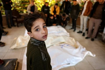 Un enfant palestinien se tient à côté des corps de quatre membres d'une même famille tués dans une frappe israélienne qui a touché leur tente près de Khan Younès dans le sud de la bande de Gaza, le 18 janvier 2025