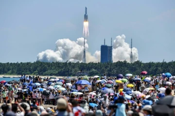 Une foule regarde le décollage de la fusée transportant le deuxième des trois modules dont la Chine a besoin pour compléter sa nouvelle station spatiale Tiangong, le 24 juillet 2022 à Wenchang (sud de la Chine)