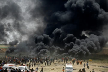 Des manifestants palestiniens brûlent pneus face à la barrière de sécurité entre Israël et la bande de Gaza, lors de nouvelles protestations à l'est de Jabaliya, le 13 avril 2018 
