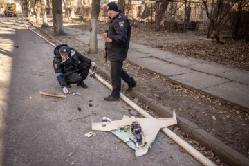Des policiers ukrainiens inspectent un drone russe abattu dans les environs de l'Académie nationale des sciences, touchée par une frappe, à Kiev, le 22 mars 2022