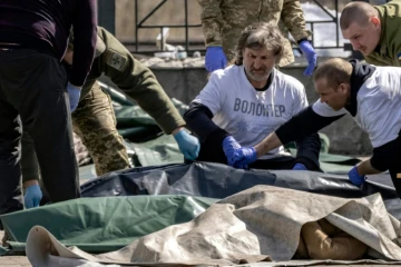 Des soldats ukrainiens enveloppent les corps des victimes d'une attaque de missiles russes sur la gare de Kramatorsk, le 8 avril 2022 dans la régin du Donbass, dans l'est de l'Ukraine