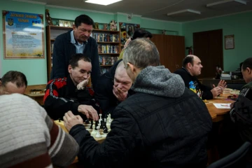 Viktor Jouravski (debout), directeur de la pension neuropsychiatrique pour hommes de Novo-Bilytsky regarde des patients jouer aux échecs, le 12 mars 2022 à Kiev