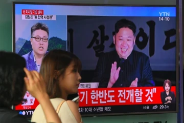 Une sud-coréenne passe devant une télévision diffusant une vidéo du leader nord-coréen Kim Jong-Un, après un tir de missile balistique intercontinental, dans une station de métro de Séoul, le 29 juillet 2017