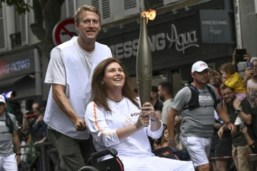 La photographe de l'Agence France-Presse (AFP) Christina Assi portant la flamme olympique (c) et le journaliste vidéo Dylan Collins (g) à Vincennes, le 21 juillet 2024