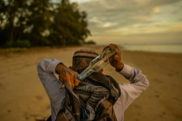 Photo du 16 septembre 2020 de Tengku Mohamad Ali Mansor en train de ramasser des bouteilles sur une plage de l'est de la Malaisie.