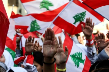 Des étudiants libanais agitent des drapeaux libanais lors d'une manifestation antigouvernementale à Saïda, dans le sud du Liban, le 6 novembre 2019