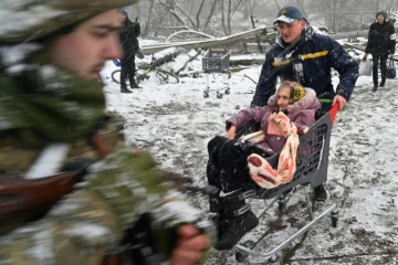 Un sauveteur transporte une femme âgée lors de l'évacuation de la ville d'Irpin, au nord-ouest de Kiev, le 8 mars 2022