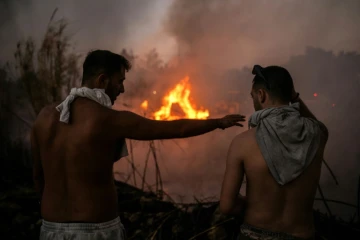 Deux personnes se tiennent devant l'incendie à Penteli, dans la banlieue d'Athènes, le 12 août 2024