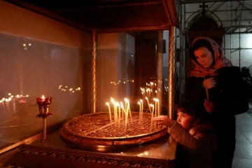 Une chrétienne et son fils allument des cierges le 20 décembre 2016 dansl'Eglise de la Nativité, à Béthléem en Cisjordanie, où Jésus-Christ est né selon la Bible