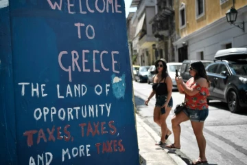 Des graffitis sur les murs d'Athènes où on peut lire "Bienvenu en Grèce, terre d'opportunité, des impôts, des impôts, et encore plus d'impôts", le 18 août 2018