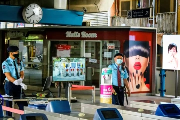 En Thaïlande, des forces de sécurité postées à un point de contrôle des températures, près d'un salon de manucure fermé, à une station du métro de Bankgok le 2 janvier 2021