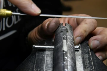 Un coutelier finalise l'abeille du ressort d'un Laguiole dans les ateliers de la Forge de Laguiole à Laguiole, dans l'Aveyron le 2 mars 2021