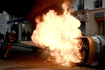 Un pompier tente d'éteindre le feu qui détruit une voiture place d'Italie à Paris, le 16 novembre 2019, en marge d'une manifestation des "gilets jaunes" 