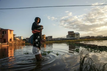 Des habitants marchent le 28 janvier 2022 dans le quartier inondé d'Ankasina à Antananarivo, capitale de Madagascar, après le passage de la tempête tropicale Ana