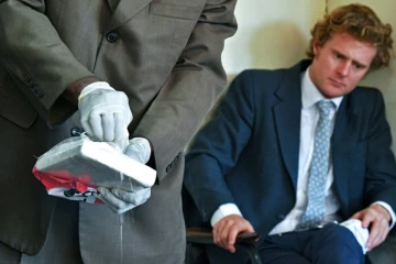 L'aristocrate britannique, Jack Alexander Wolf Marrian (D), accusé du trafic de 100 kilos de cocaïne depuis le Brésil vers le port de Mombasa, face à une plaquette de cocaïne présentée comme preuve, le 11 novembre 2016 au siège du Département d'enquête criminelle de Nairobi