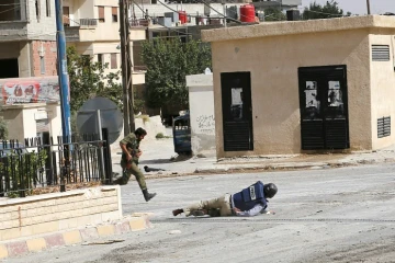 Sammy Ketz, grand reporter à l'AFP, à terre pendant des échanges de tirs dans la ville de Maaloula en Syrie, alors qu'un militaire syrien traverse en courant, le 18 septembre 2013
