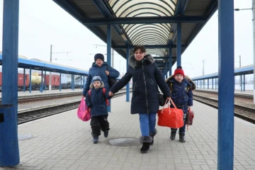 Galyna Kanouka (C) avec ses deux enfants et sa mère Svitlana Nataloukha arrivent à la gare de Lviv, en Ukraine, le 16 mars 2022, après avoir décidé de revenir de Pologne où elles s'étaient enfuies au début de la guerre