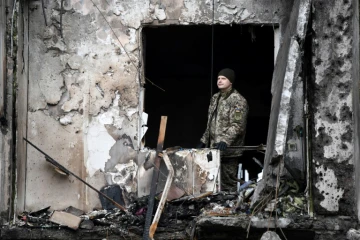 Un membre des forces ukrainiennes dans un immeuble touché par une frappe russe dans la banlieue de Kiev, le 25 février 2022

