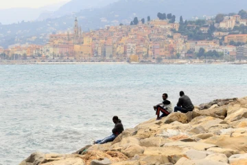 Des migrants regardent la mer à Vintimille, à la frontière franco-italienne, tout près de la ville française de Menton, en arrière-plan, le 13 juin 2015