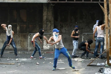 Des jeunes Palestiniens lancent des pierres sur les forces de sécurité israéliennes lors de heurts à Hébron, le 4 octobre 2015