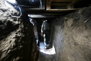 Un soldat ukrainien marche dans une tranchée creusée face à l'armée russe près de la ville de Mikolaïv, dans le sud de l'Ukraine, le 12 juin 2022