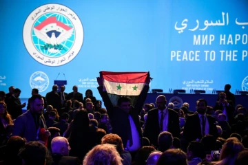 Un homme brandit un drapeau de l'opposition syrienne devant des délégués attendant l'ouverture de la réunion du Congrès du dialogue national syrien organisé à Sotchi par Moscou, le 30 janvier 2018
