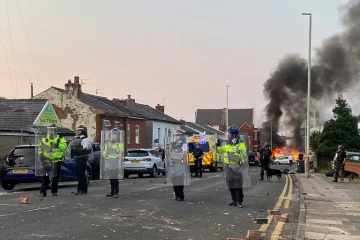 Un feu allumé par des manifestants près de la mosquée de Southport en Angleterre, gardée par des policiers, le le 30 juillet 2024 au lendemain d'une attaque meurtrière contre des enfants