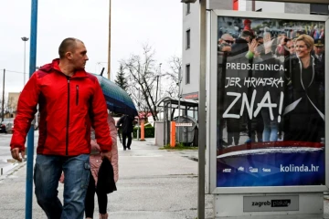 Un Croate regarde une affiche de la présidente Kolinda Grabar-Kitarovic, candidate à sa propre réelection, le 21 décembre 2019 à Zagreb