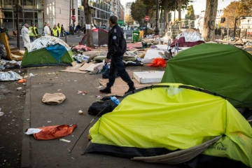 Un policier marche au milieu de tentes de migrants près du Quai de Jemmapes (nord de Paris), le 31 octobre 2016
