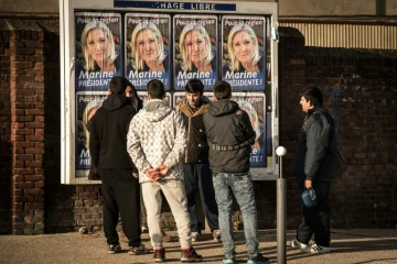 Des migrants regardent les panneaux électoraux à Calais avec en affiche la tête de liste FN de la région Nord, Marine Le Pen, le 7 décembre 2015