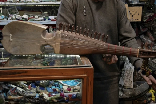 Gull Agha, un joueur amateur afghan de rubab, présente l'instrument dans un magasin à Herat, le 21 décembre 2024 ( AFP / Wakil KOHSAR )