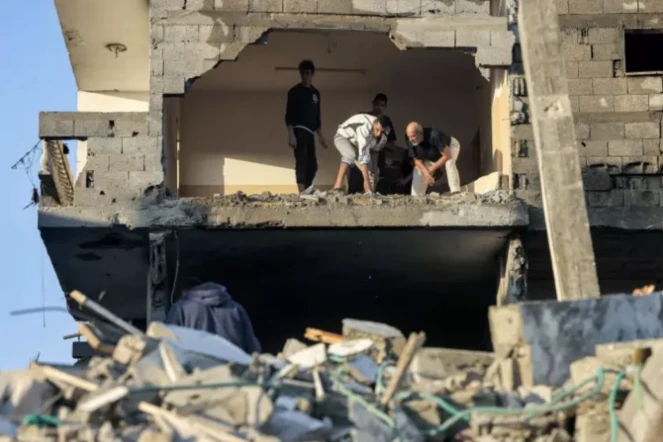 Des Palestiniens fouillent les décombres d'un immeuble détruit par un bombardement israélien à Rafah, le 19 octobre 2023 dans le sud de la bande de Gaza ( AFP / MOHAMMED ABED )