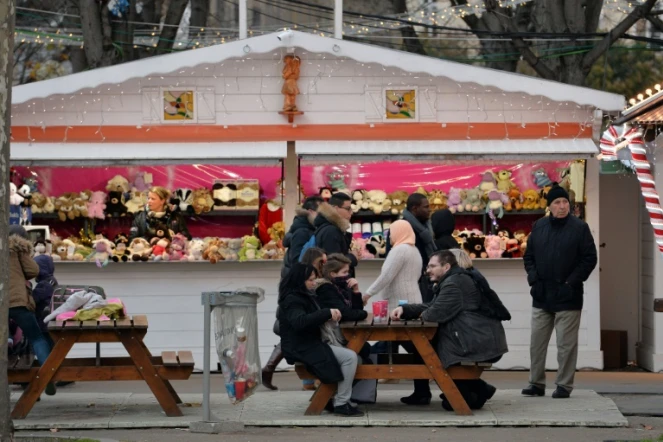 Des personnes s'asseoient devant un stand de jouets, au marché de Noël à Paris, le 24 décembre 2015 