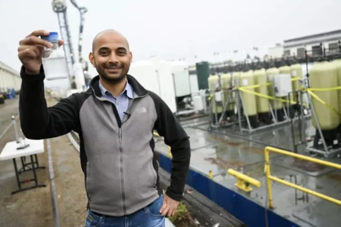 Gaurav Sant, directeur de l'Institut de gestion du carbone de l'université UCLA, montre la poudre blanche dans laquelle est piégéé le CO2 contenu dans l'eau de mer, grâce au projet SeaChange installé sur une barge, le 12 avril 2023 au port de Los Angeles ( AFP / Patrick T. Fallon )