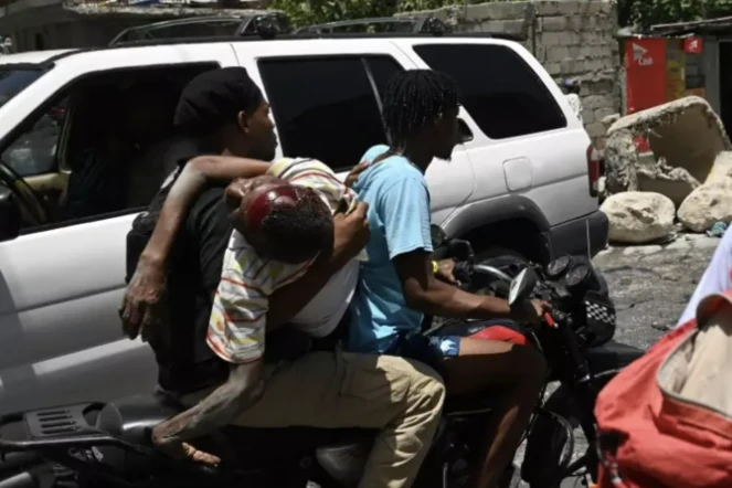Un homme blessé transporté en moto à l'hôpital. Il aurait été atteint par balle pendant des violences liées aux gangs à Port-au-Prince le 15 août 2023 ( AFP / Richard PIERRIN )