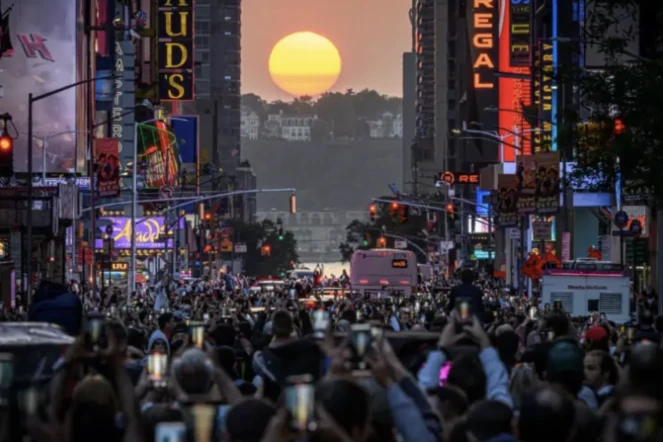 Le soleil aligné entre les rangées de gratte-ciel qui quadrillent l'île de Manhattan, à New York, le 30 mai 2023. Le phénomène qui a lieu quatre fois par an est connu sous le nom de "Manhattanhenge" et fait descendre des centaines de New-Yorkais dans les rues ( AFP / Ed JONES )