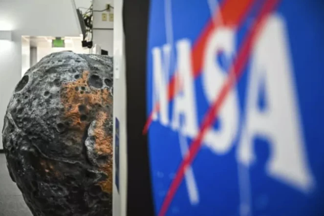 Le logo de la Nasa devant une réplique de l'astéroïde Psyché au centre spatial Kennedy en Floride, le 10 octobre 2023 ( AFP / CHANDAN KHANNA )