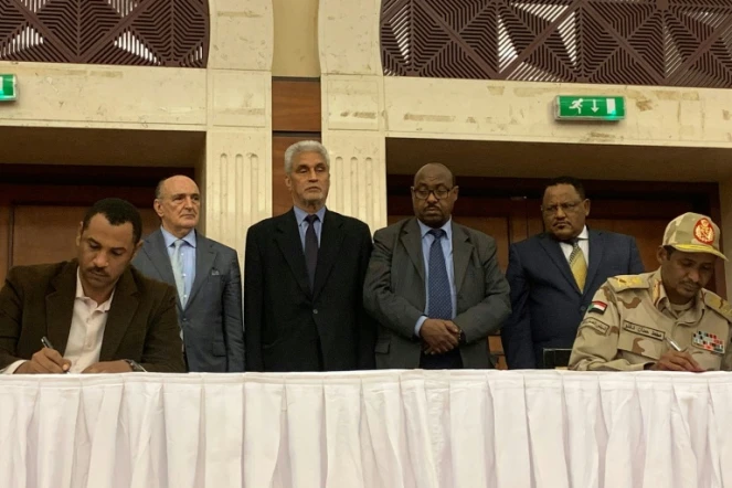 Le numéro deux du Conseil militaire, au pouvoir au Soudan, Mohamed Hamdan Daglo (D) signe avec un leader du mouvement de contestation (G) un accord entérinant le partage du pouvoir pendant la période transition, en présence de médiateurs éthiopiens et de l'Union africaine, le 17 juillet 2019 à Khartoum