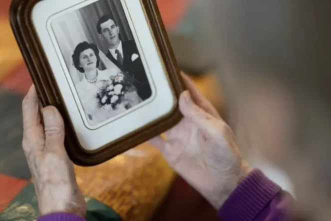 Jeanne Tournellec regarde la photo de mariage de sa sœur Catherine Tournellec, violée par un soldat américain, et de son beau-frère Jean Salaun, chez elle à Locmaria-Plouzane, le 14 mars 2024 dans le Finistère ( AFP / Fred TANNEAU )