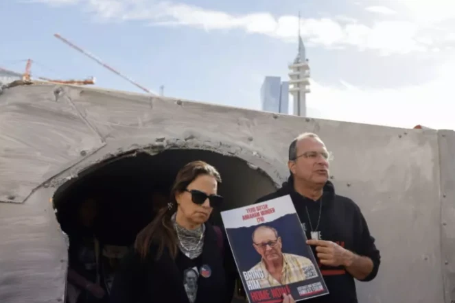 Des proches tiennent le portrait d'un otage retenu par le Hamas devant un tunnel reconstitué, le 13 avril 2024 à Tel-Aviv ( AFP / Marco Longari )